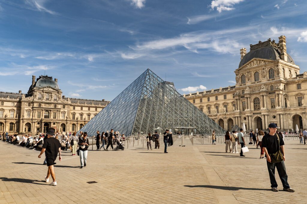 Louvre Museum pyramid with people outside.