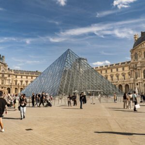Louvre Museum pyramid with people outside.
