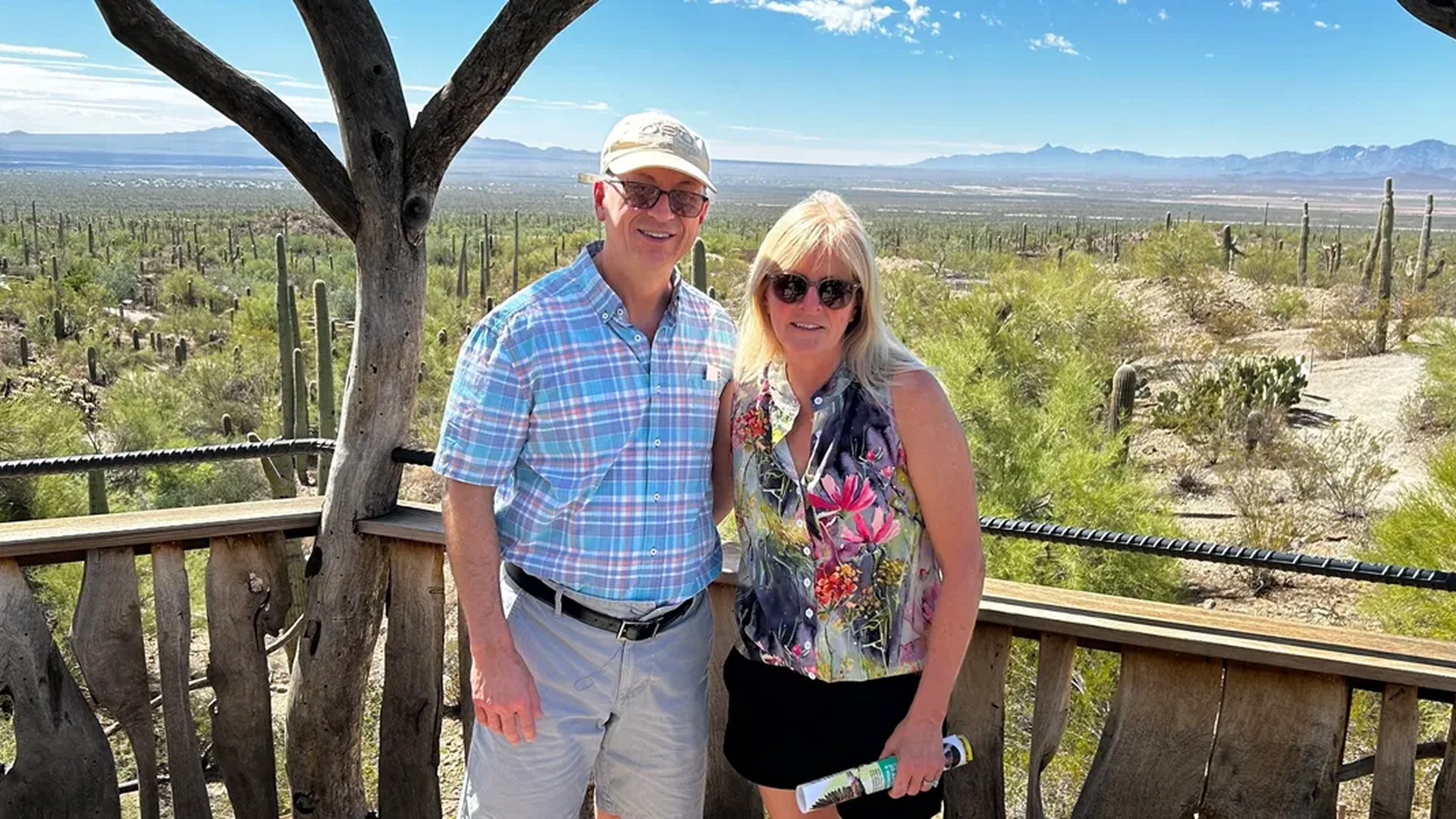 A couple posing outdoors with a scenic desert mountain backdrop.