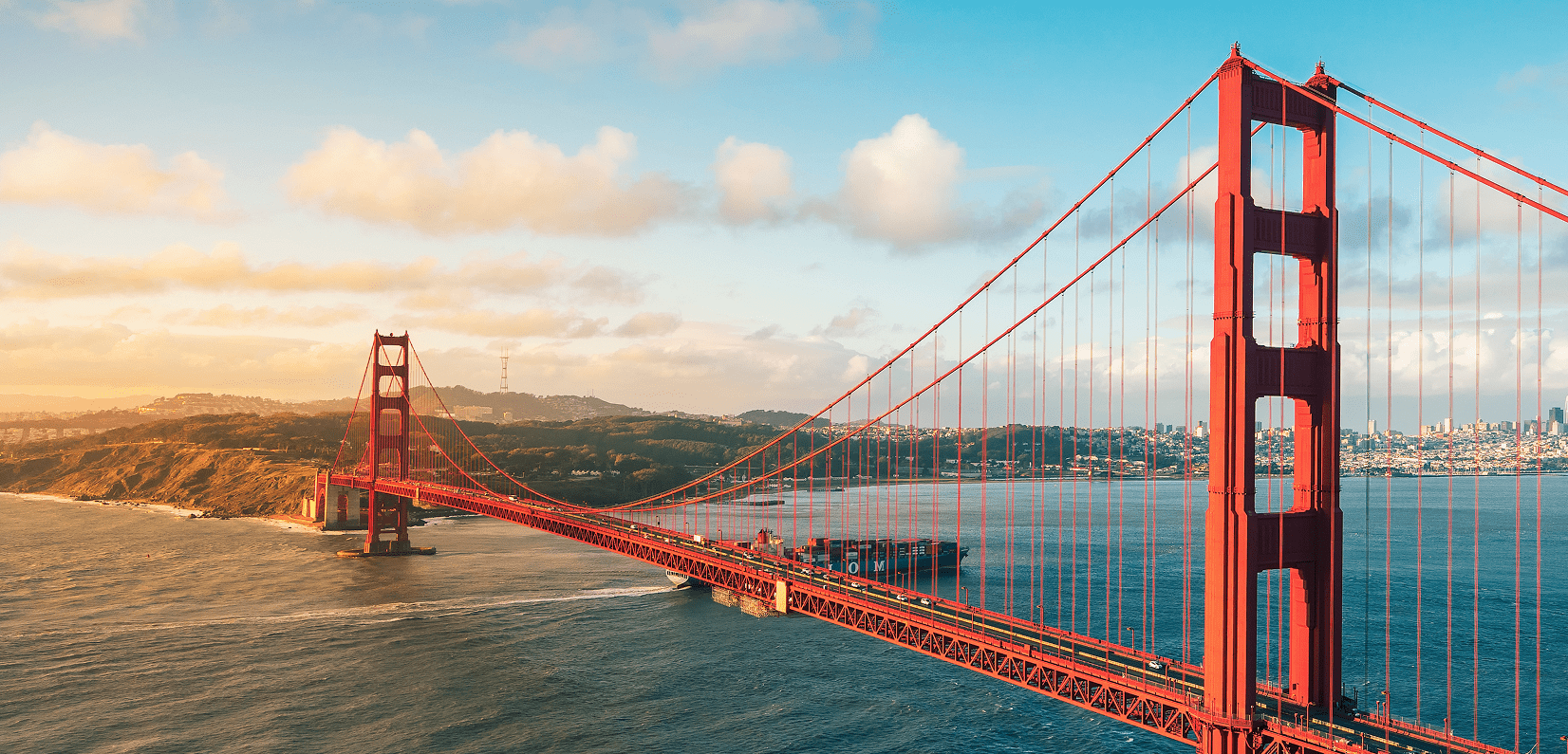 Golden Gate Bridge at sunset with a partly cloudy sky.
