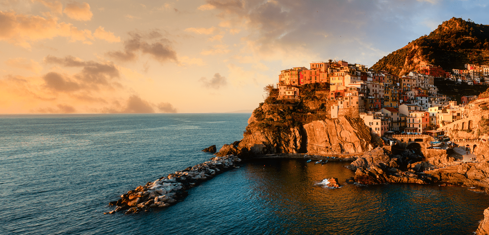 Sunset view of a coastal cliffside village with colorful buildings.