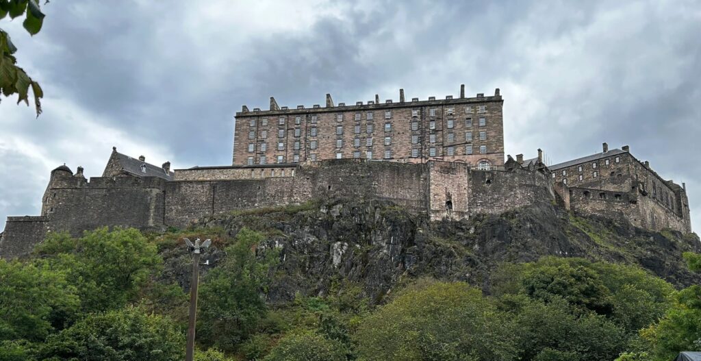 Historic fortress atop a rocky hill under a cloudy sky.