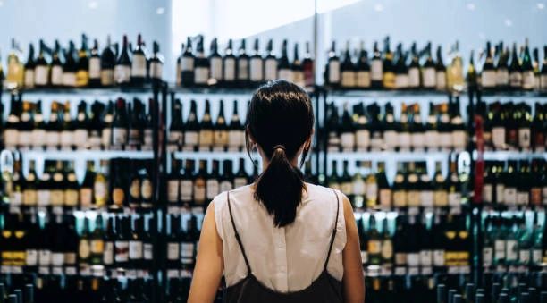 Person browsing wine bottles on store shelves.