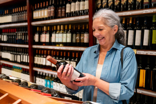 Smiling woman examining wine bottle in store