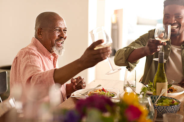 Happy senior man toasting drinks with family members during reunion celebration at home